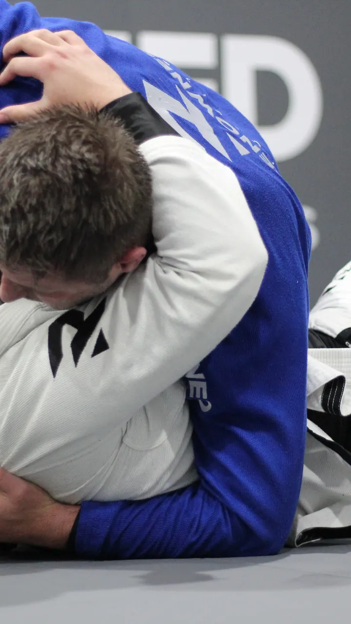 Two adults mid technique during an evening jiu jitsu class